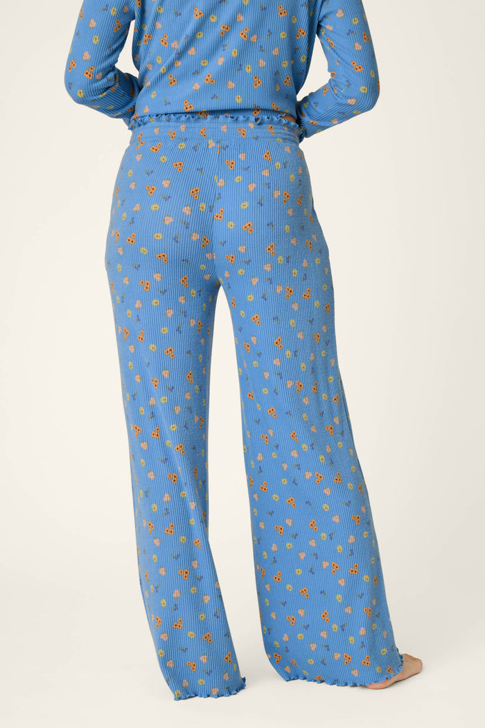 A person wearing P.J. Salvage Tiny Blooms Paris Blue Floral Print Pajama Pants is shown from the back against a plain light background.