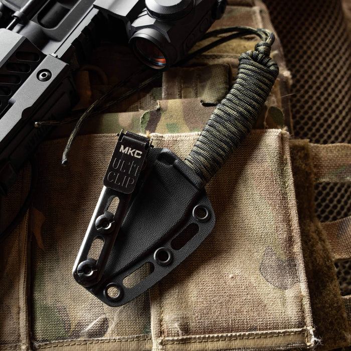 TRAIL GOAT knife with black and dark camo handle on tactical gear, showcasing its durable design for outdoor use.