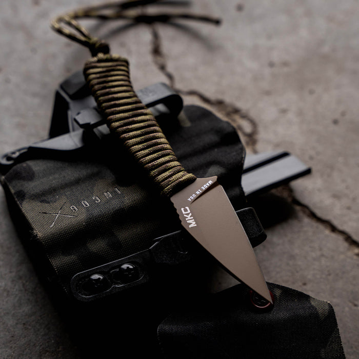 TRAIL GOAT knife in Coy/Multicam with paracord handle, resting on a tactical holster and gear.