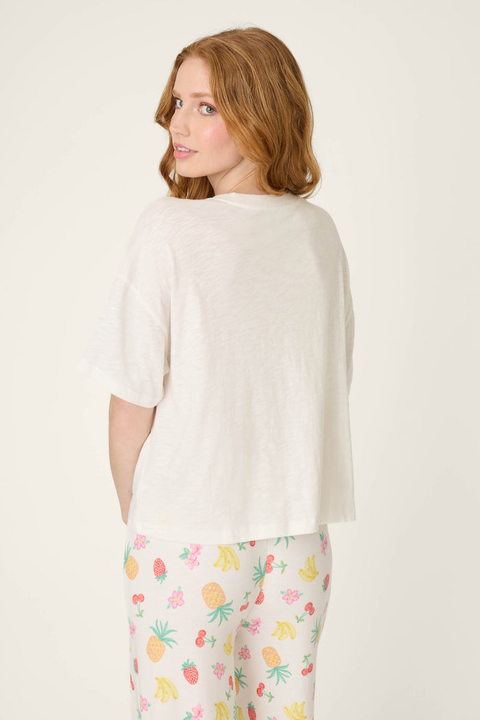 White fabric with vibrant multi-colored fruit patterns; smooth surface and playful, summery design.