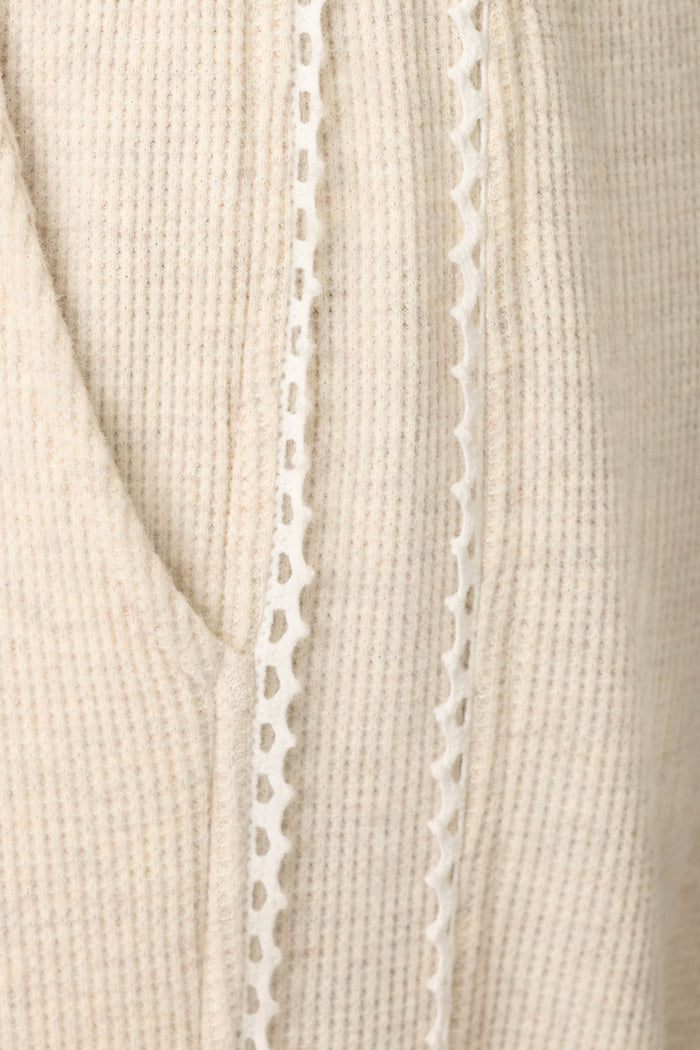 Close-up of the Weekday Waffles Oatmeal Lounge Pants by P.J. Salvage, featuring beige ribbed fabric with a decorative white lace trim running vertically alongside a seam or pocket.