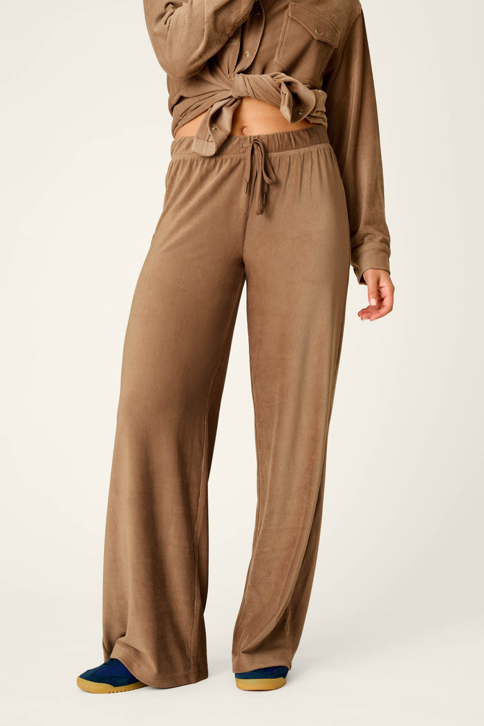 A person wearing the P.J. Salvage Western Ways Easy Itzy Corduroy Knit Lounge Pants in brown with a matching long-sleeve top, standing against a plain background. Only the lower face and body are visible.