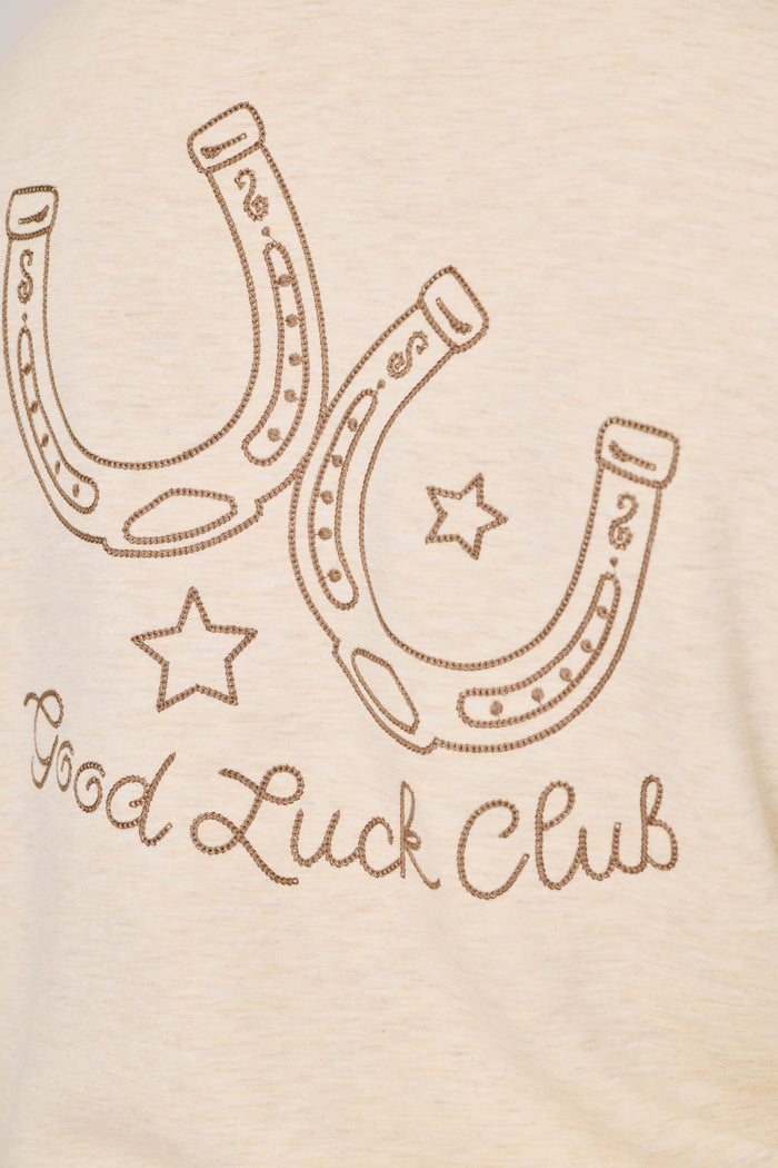 Two outlined horseshoes and two stars are positioned above the words “Good Luck Club,” written in cursive, on the light beige fabric of the P.J. Salvage Western Ways Good Luck Club Over Night Pullover.
