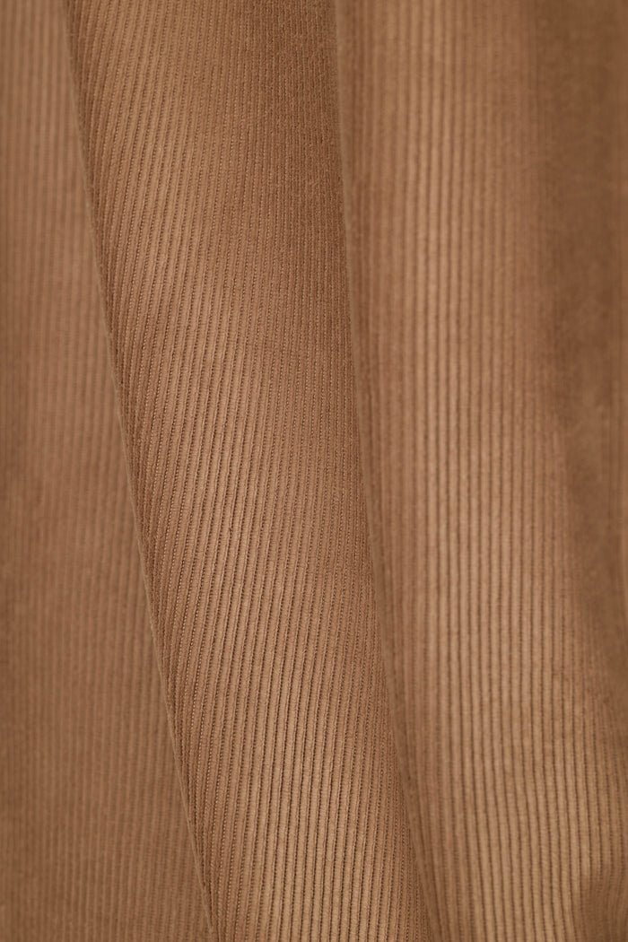 Close-up of a brown corduroy fabric texture with vertical ribs and soft folds.