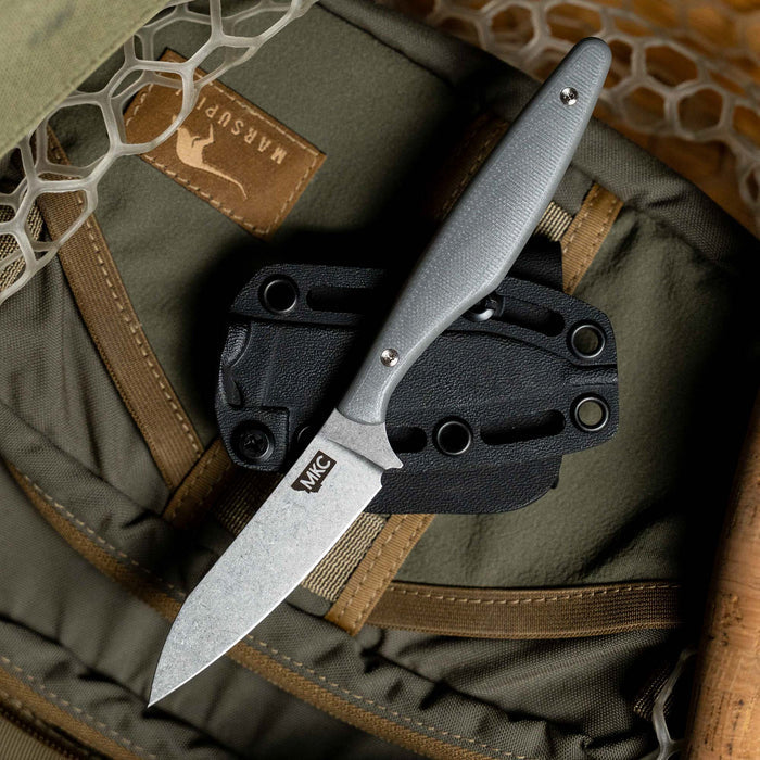 WESTSLOPE knife in grey with a textured handle, resting on a black sheath atop a tactical backpack.