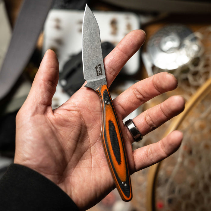 Hand holding the WESTSLOPE knife featuring an orange and black handle, showcasing its sleek blade design.