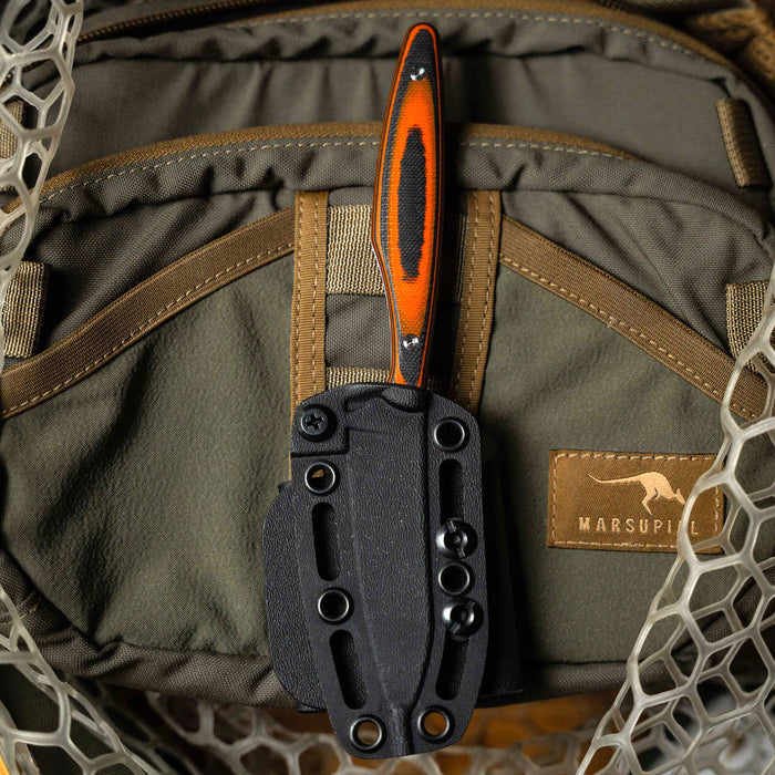 Orange and black WESTSLOPE knife in a sheath resting on a green tactical backpack, showcasing its rugged design.