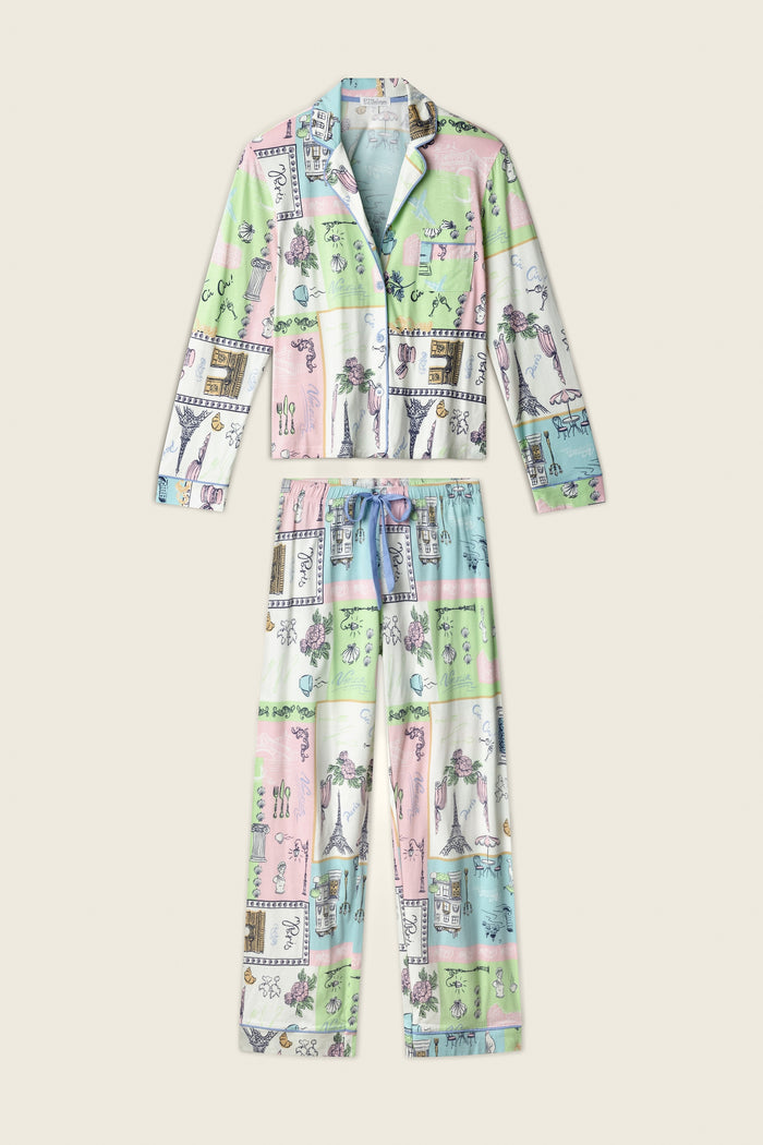 The Whimsy Postcards From Paris PJ Set by P.J. Salvage is a two-piece pajama with a button-up long-sleeve top and drawstring pants, featuring a pastel patchwork of illustrations on a cream background.